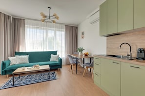 A compact living space with a sofa, a dining table, and a kitchenette. - Śląska 416 | Gym | AC & Parking (Gdańsk)