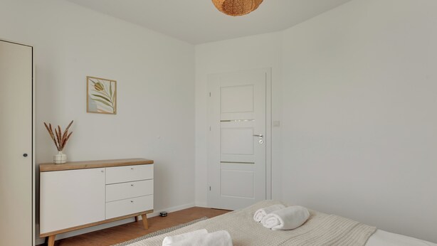 A minimalist bedroom with a bed, a dresser, and a door. - Śląska 416 | Gym | AC & Parking (Gdańsk)