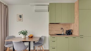 A modern kitchen with a dining area, featuring a table with chairs, a plant, and a fruit bowl. - Śląska 416 | Gym | AC & Parking (Gdańsk)