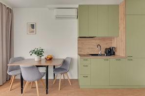 A modern kitchen with a dining area, featuring a table with chairs, a plant, and a fruit bowl. - Śląska 416 | Gym | AC & Parking (Gdańsk)