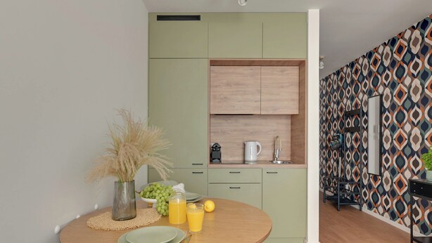 Cocina compacta con comedor, que incluye una mesa redonda con platos, cubiertos y un jarrón con plantas secas.