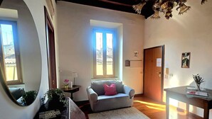 A room with a sofa, a table, a mirror, a window, and a door. - Bright Apartment in Trastevere (Roma)