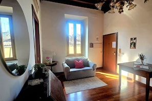 Ein Zimmer mit einer Couch, einem Tisch, einem Spiegel, einem Fenster und einer Tür.