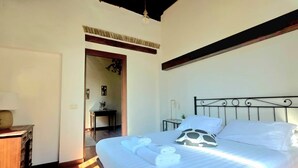 A bedroom with a bed, a nightstand, a lamp, and a wooden dresser. - Bright Apartment in Trastevere (Roma)