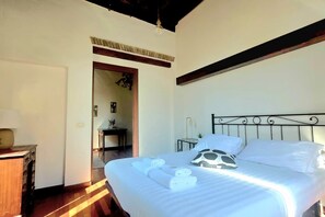 Ein Schlafzimmer mit einem Bett, einem Nachttisch, einer Lampe und einer hölzernen Kommode.