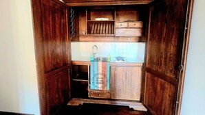 A wooden cabinet with shelves and drawers, a hanging rack, and a towel rack. - Bright Apartment in Trastevere (Roma)