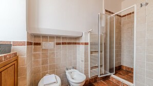 A bathroom with a toilet, bidet, and shower area. - Bright Apartment in Trastevere (Roma)
