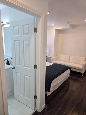 A bedroom with a bed, a white sofa, and a door leading to a bathroom. - Skytop ar Over The Rhine 6-bedroom 4 bath Cincinnati (Cincinnati)