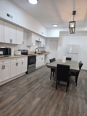 A modern kitchen with white cabinets, a dining table, and a built-in oven. - Skytop ar Over The Rhine 6-bedroom 4 bath Cincinnati (Cincinnati)
