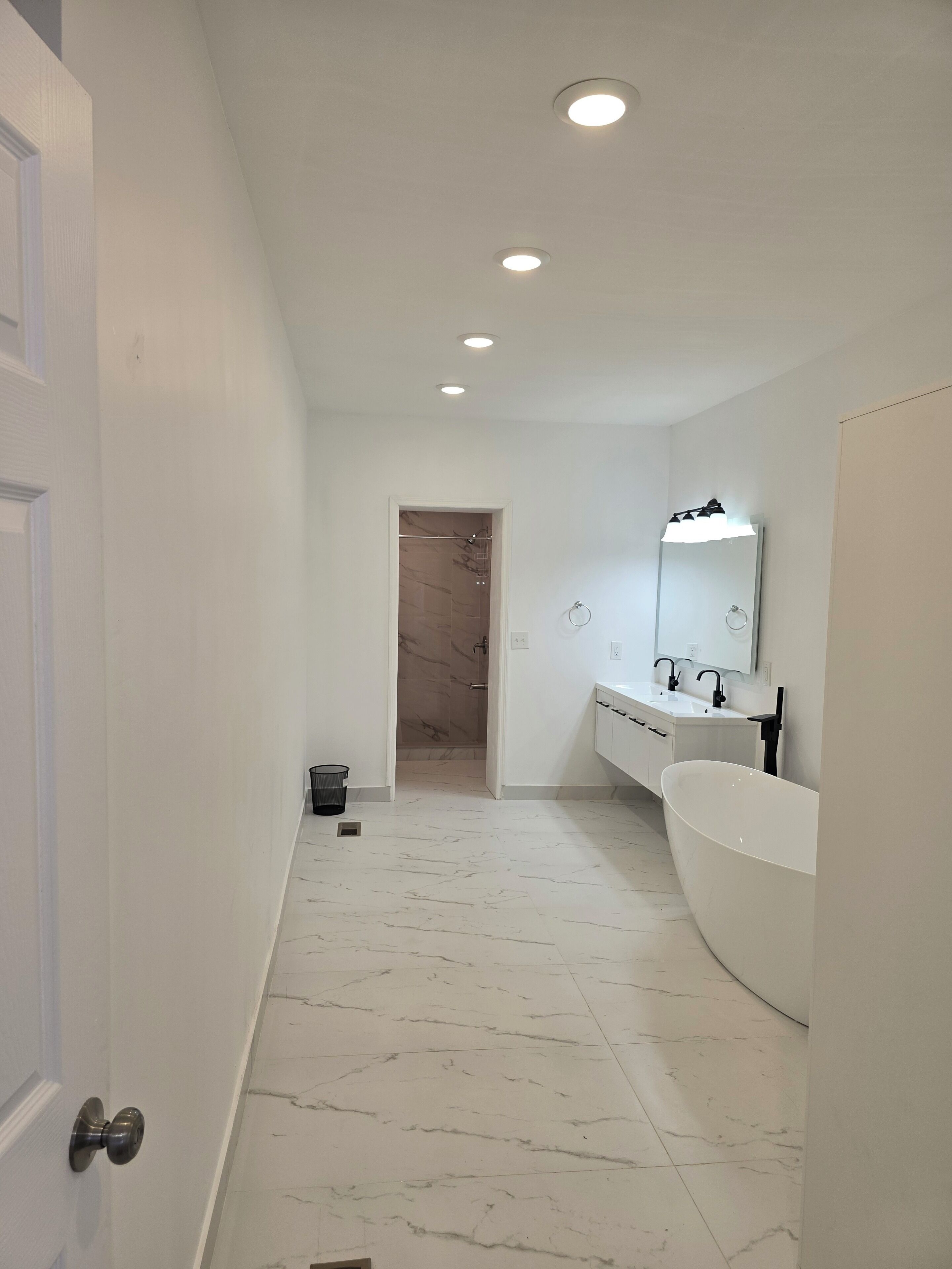 Une salle de bain moderne avec une grande baignoire blanche, un meuble-lavabo avec un miroir et un espace douche.