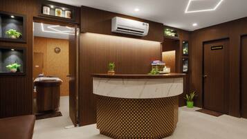 A reception area with a wooden reception desk, a clock, and a wall-mounted air conditioner.