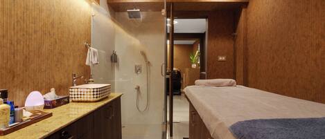 A modern bathroom with a shower, a sink, and a bed.