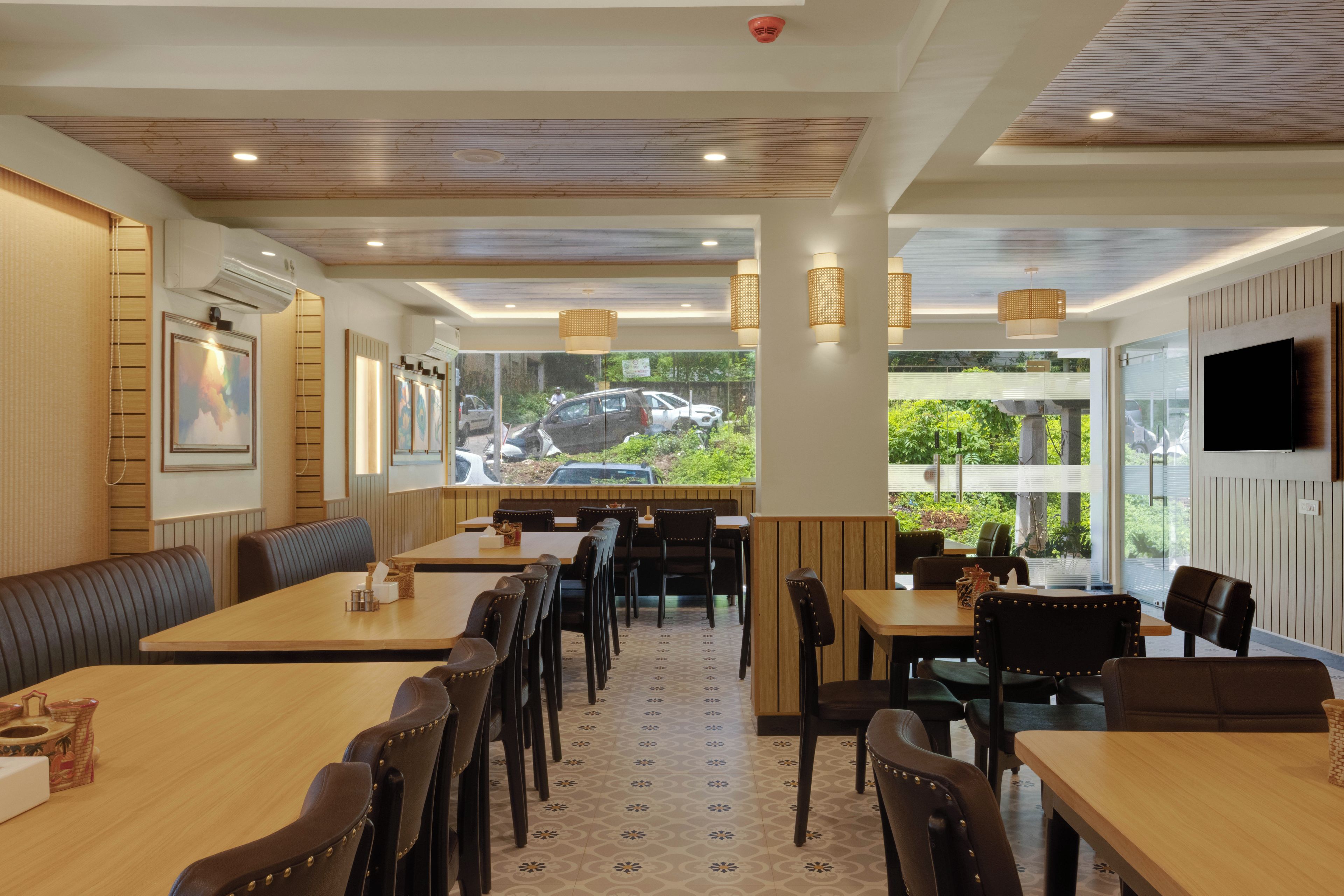 Un restaurant avec des tables et des chaises en bois, un sol à motifs et une vue sur l’extérieur.