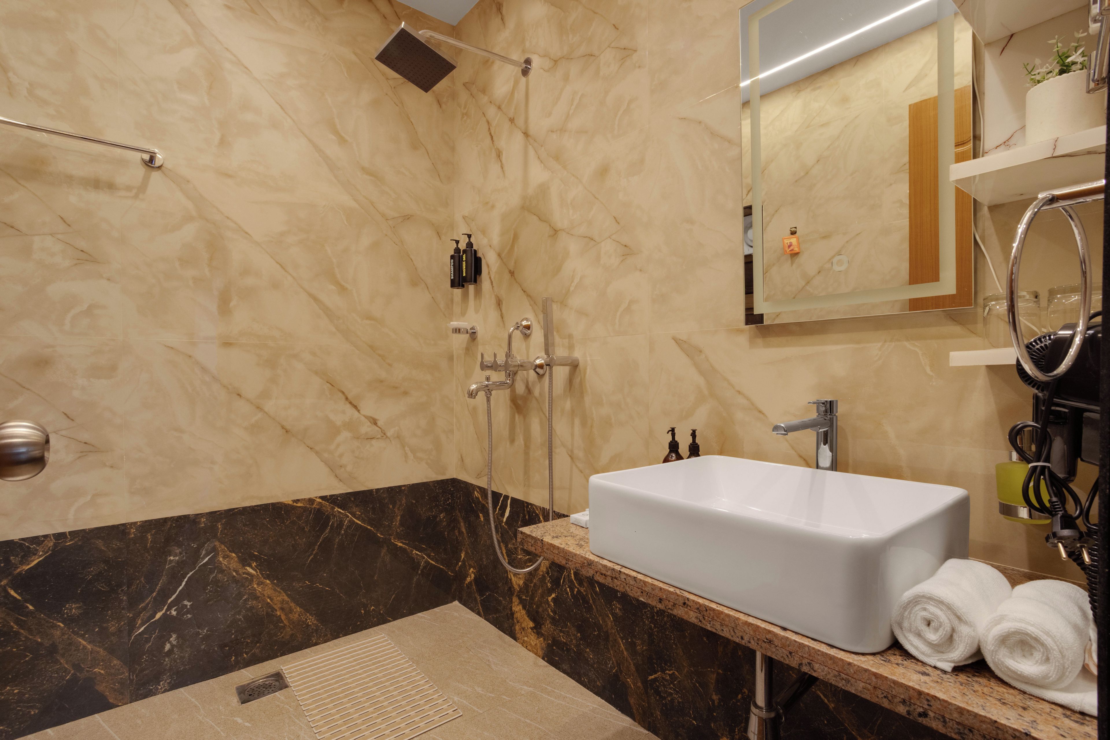 Ein modernes Badezimmer mit einem großen weißen Waschbecken, einer Handbrause und einem Spiegel über dem Waschbecken.