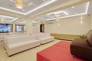 A spacious room with white sofas, a red rug, and a brown chair.