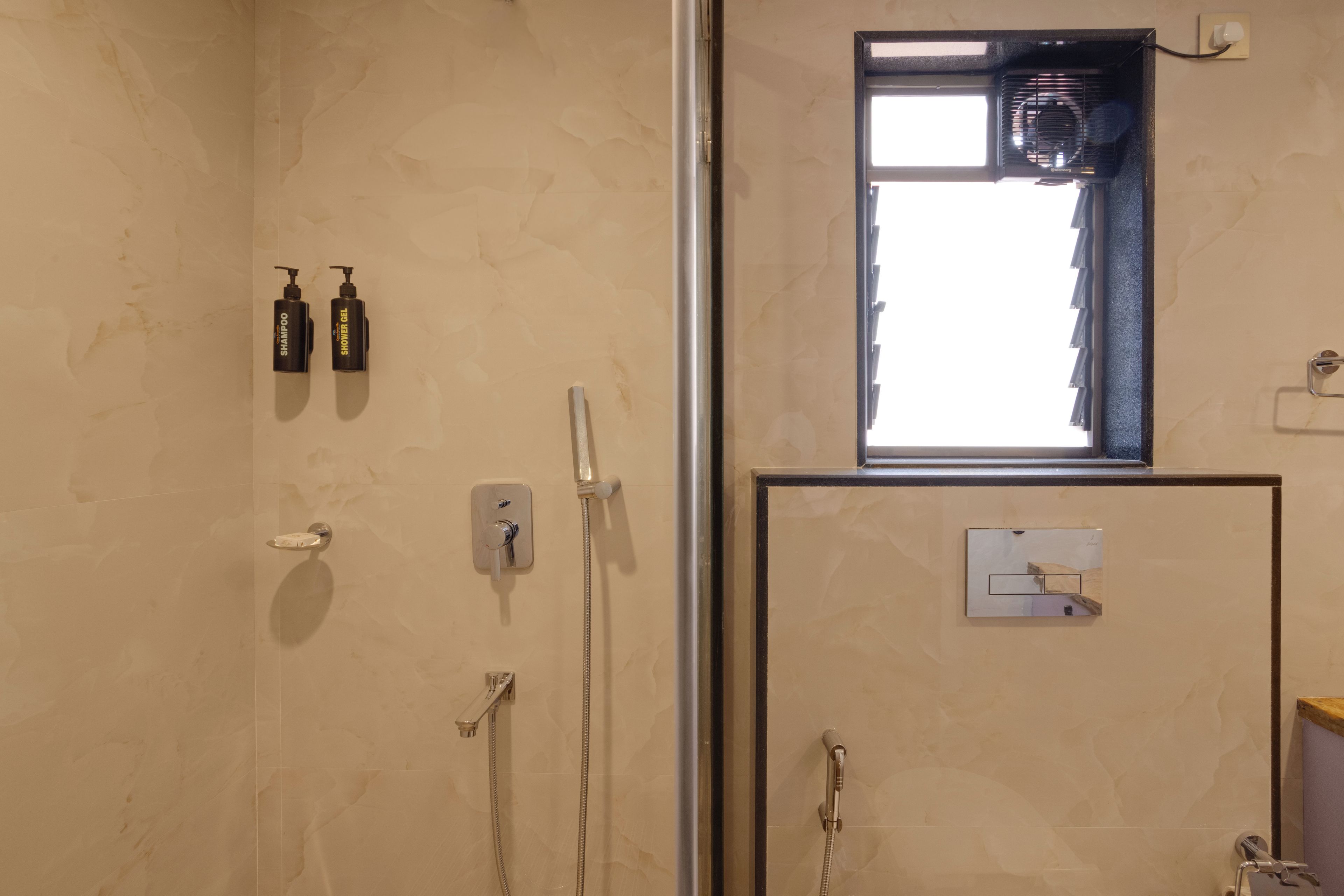 Un bagno con doccia, uno specchio e due flaconi di shampoo e bagnoschiuma.