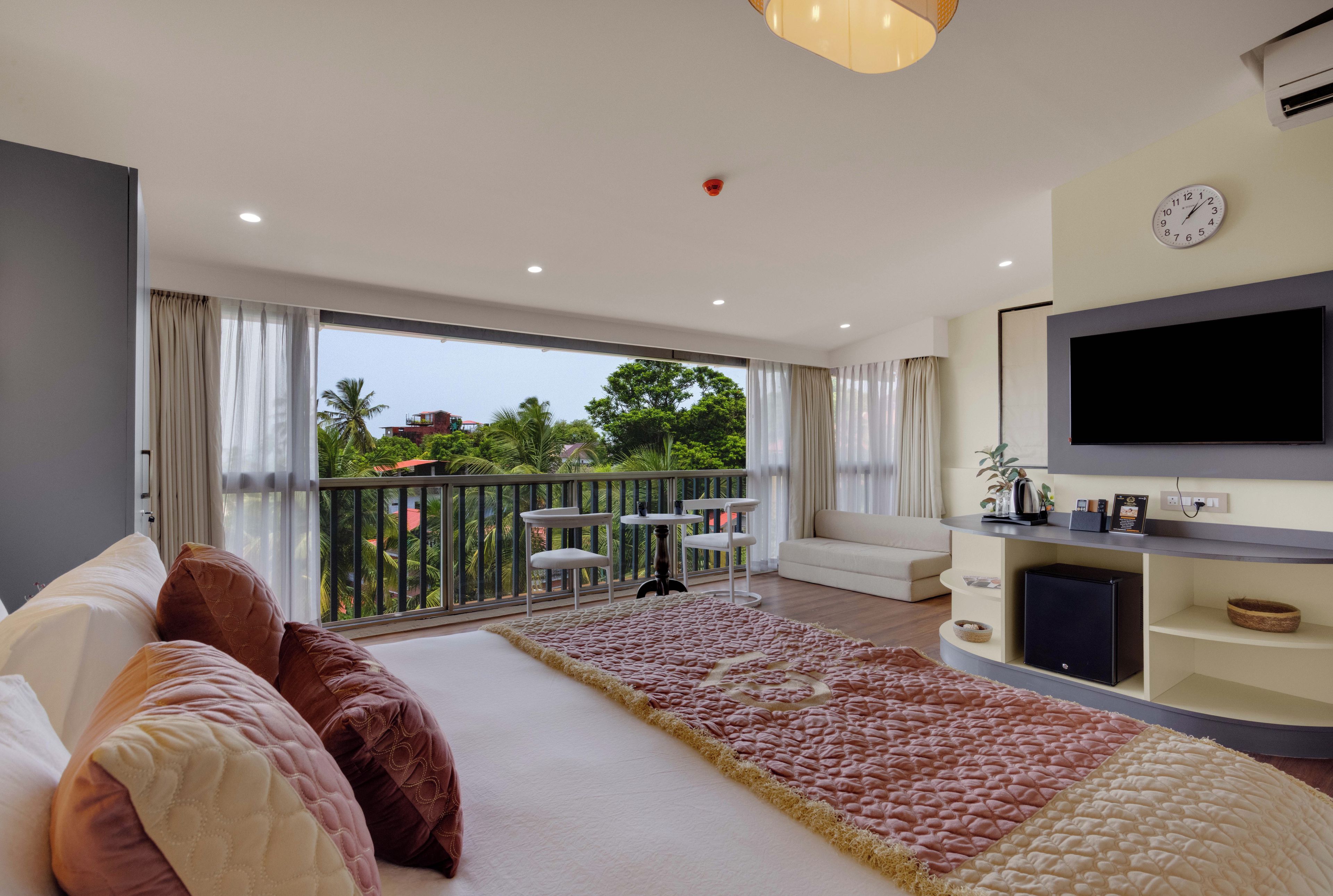 Un salon moderne avec un canapé, un téléviseur à écran plat et un balcon offrant une vue sur la verdure.