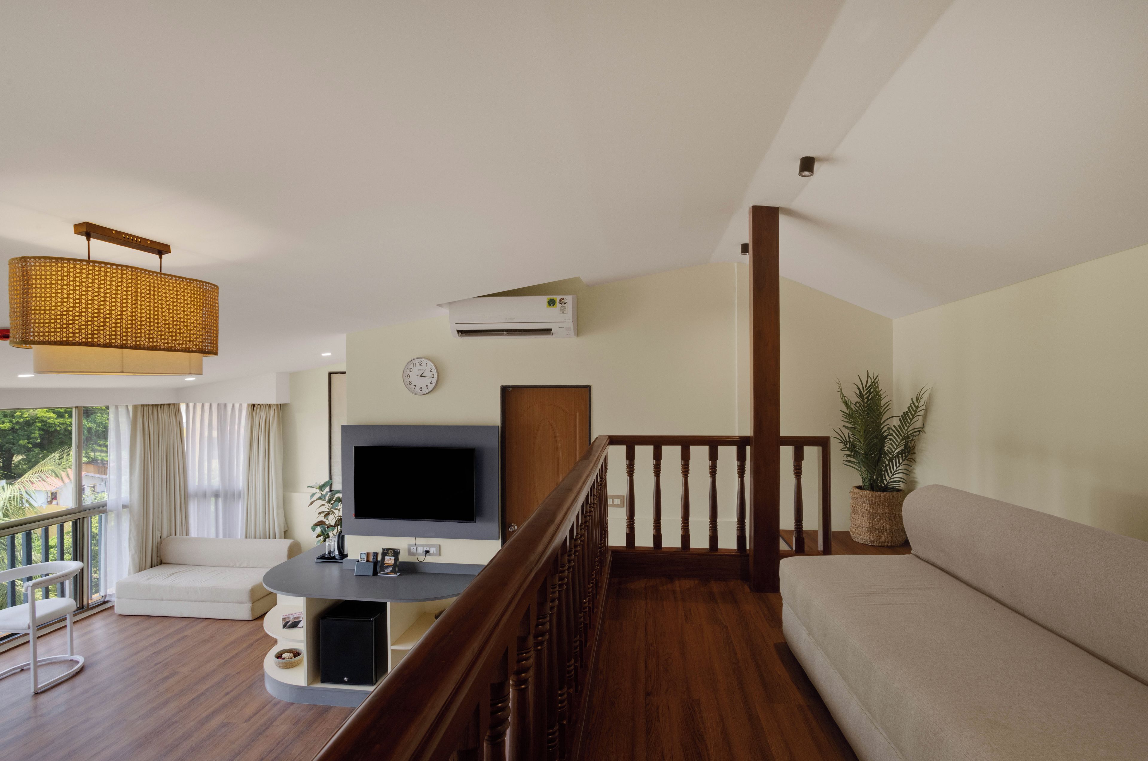 Una sala de estar con televisor, sofá y una escalera.
