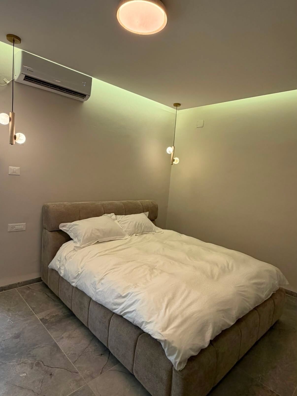 Un dormitorio con cama, aire acondicionado y luces colgantes.