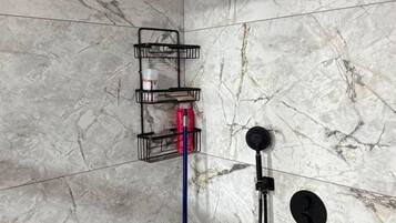 A shower area with a handheld showerhead, a handheld shower attachment, and a wall-mounted shower head.