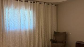 Quarto de hotel com uma cama grande, uma cadeira, uma escrivaninha e um lustre moderno.