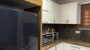 A modern kitchen with a built-in microwave, a stainless steel refrigerator, and wooden cabinetry.