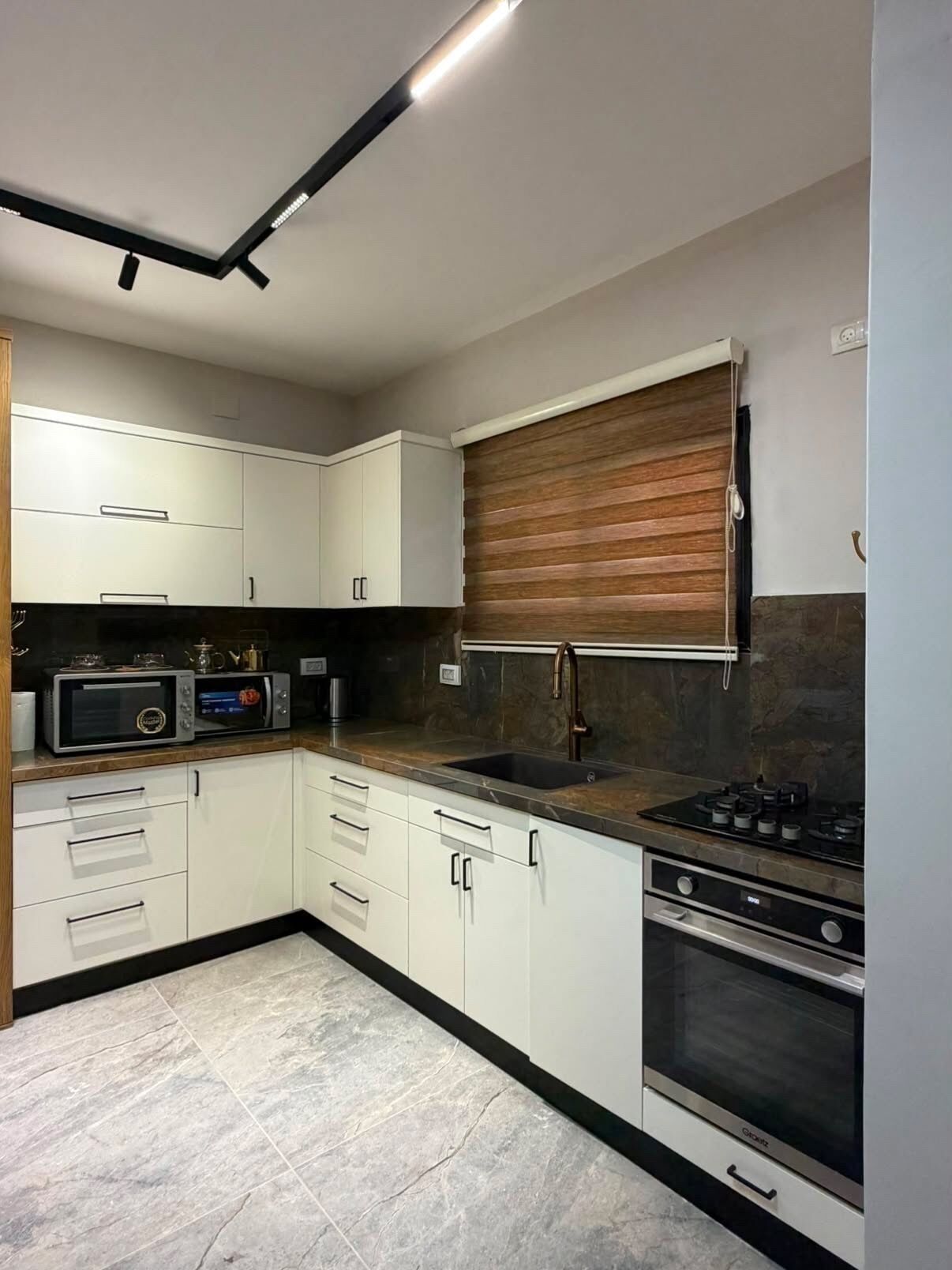 Een moderne keuken met witte kastjes, een ingebouwde oven, een gasfornuis en een magnetron.