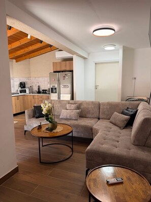 A modern living room with a sectional sofa, a coffee table, and a remote control on a side table.