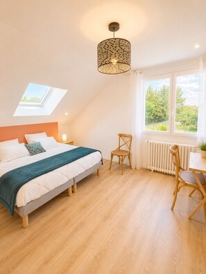Ein Schlafzimmer mit Bett, Tisch, Stuhl, Fenster mit Aussicht und einem Oberlicht.