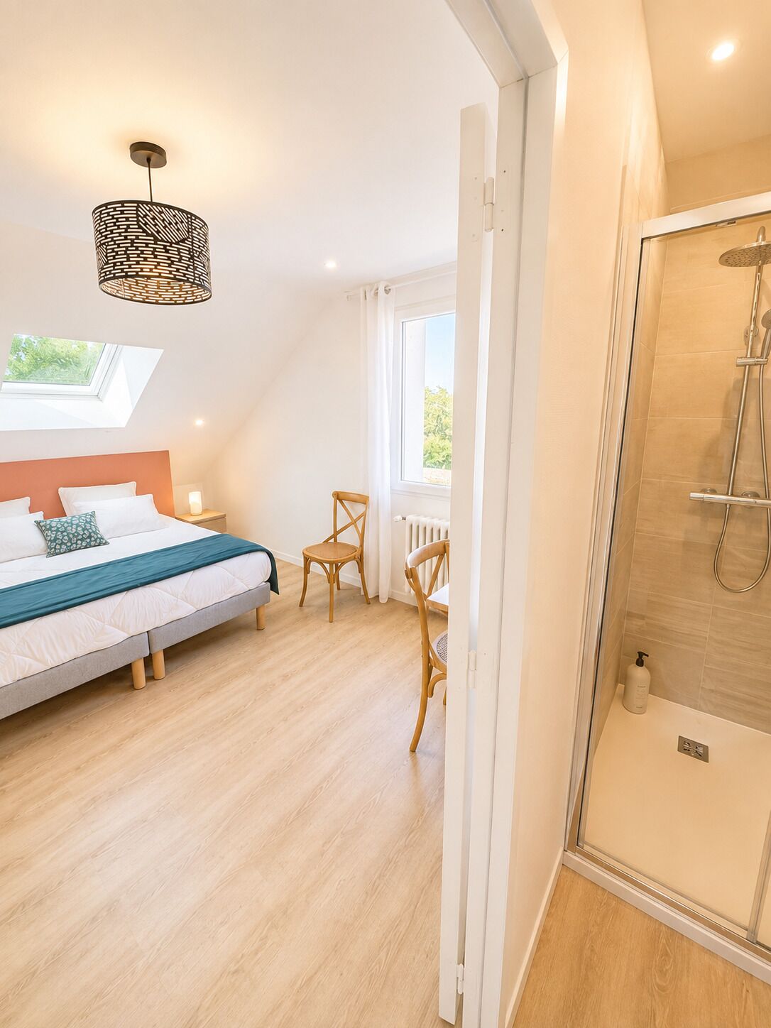 Une chambre à coucher comprenant un lit, une chaise, une table de chevet, une fenêtre et un espace douche.