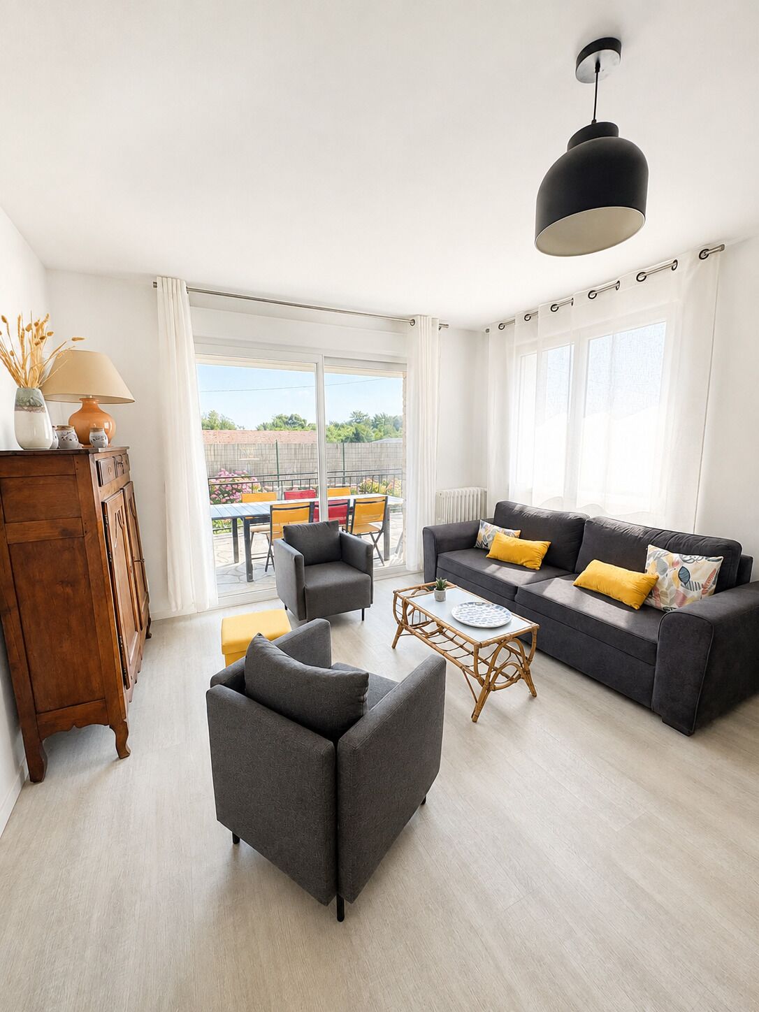 A modern living room with a sofa, armchairs, a coffee table, and a wooden cabinet.