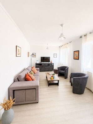 En moderne stue med sofa, lænestole, sofabord og tv.