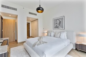 A modern bedroom with a large bed, bedside lamps, a hanging light fixture, and a framed artwork on the wall. - Elegant 3 BR | Wasl 1 (Dubai)