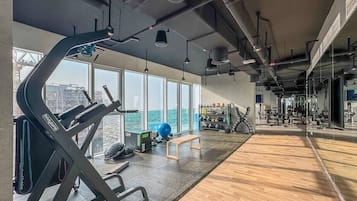 Une salle de sport équipée de machines de cardio, de poids et d’un banc.