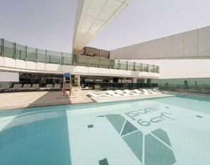 Una piscina en la azotea con sillones de descanso y barandilla de cristal.