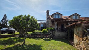 A stone house with a tiled roof, a stone staircase, and a well-maintained lawn.
