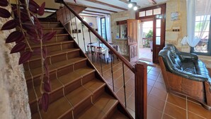 A staircase with wooden steps and metal railings, leading to a dining area with a table and chairs.