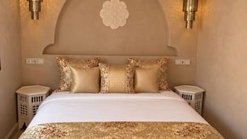 Une chambre à coucher avec un grand lit, des coussins décoratifs, un luminaire suspendu et des lampes fixées au mur.