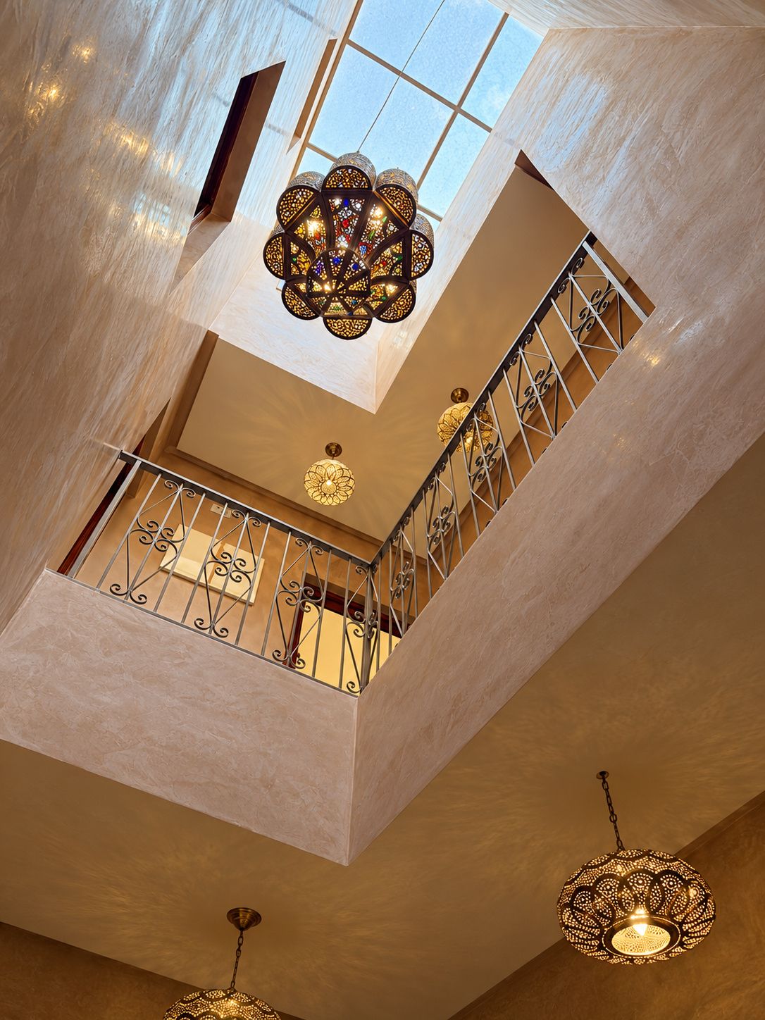 Un intérieur à plusieurs niveaux, doté d’un escalier, de lustres décoratifs et d’une verrière.