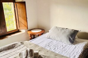 A bedroom with a bed, a window, a bedside table, and a chair. - Casa Uno -Organic Farmhouse Podere Acquarello in the Maremma  - panoramic views. (Toscana)