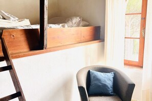 Une chambre avec un lit superposé, une chaise avec un coussin et une fenêtre donnant sur un beau paysage.