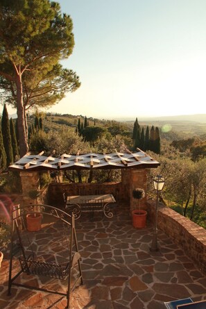 A stone patio with a pergola, a swing, and a view of a hilly landscape. - Casa Uno -Organic Farmhouse Podere Acquarello in the Maremma  - panoramic views. (Toscana)