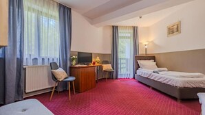 A hotel room with a bed, a desk with a computer, a chair, and a sofa.