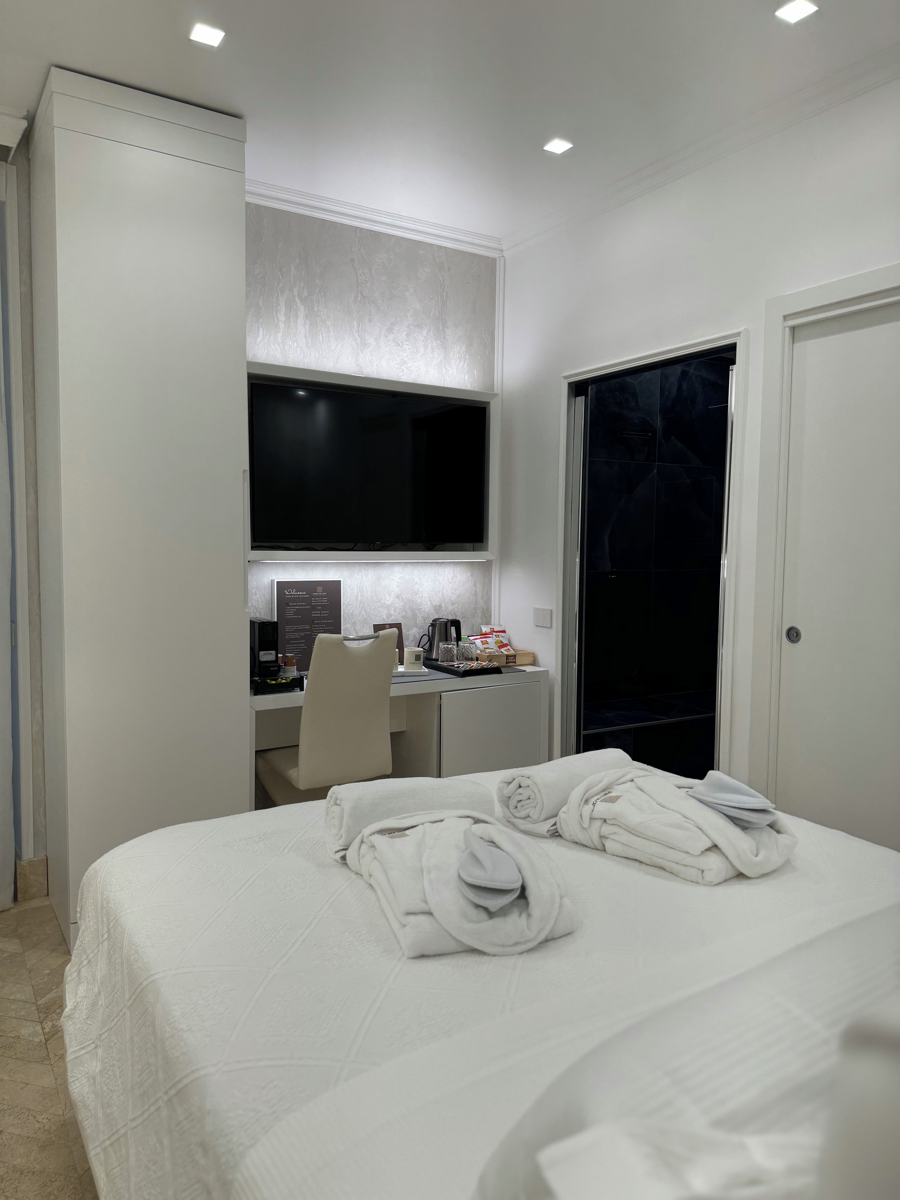 Una habitación de hotel con cama, escritorio con computadora, televisor y armario.