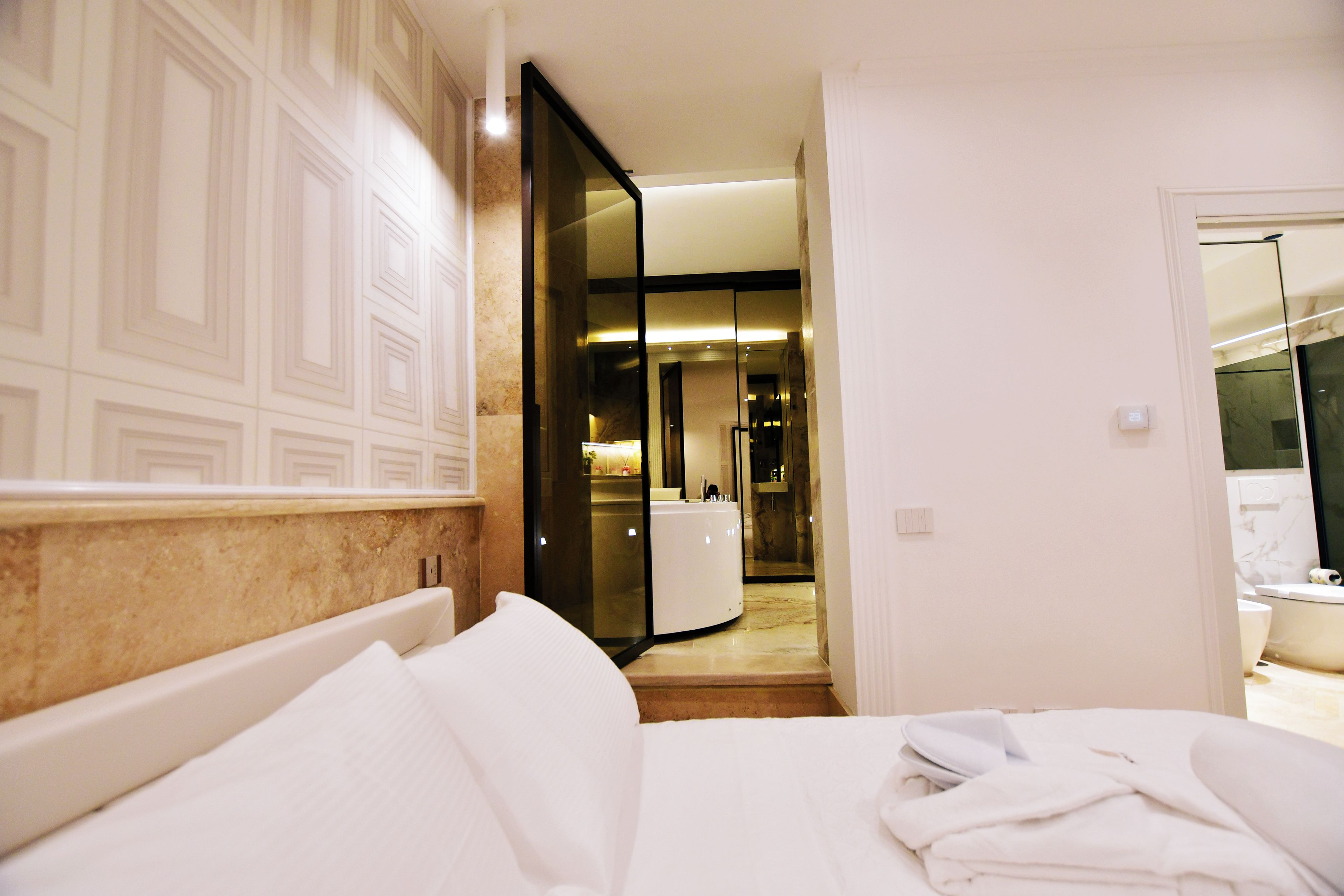 Une chambre d’hôtel avec un lit, une salle de bain avec un miroir et un couloir menant à une autre pièce.