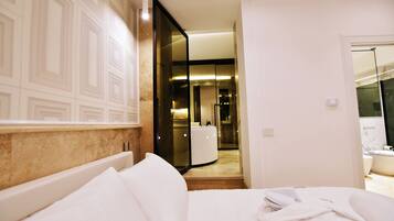 Une chambre d’hôtel avec un lit, une salle de bain avec un miroir et un couloir menant à une autre pièce.