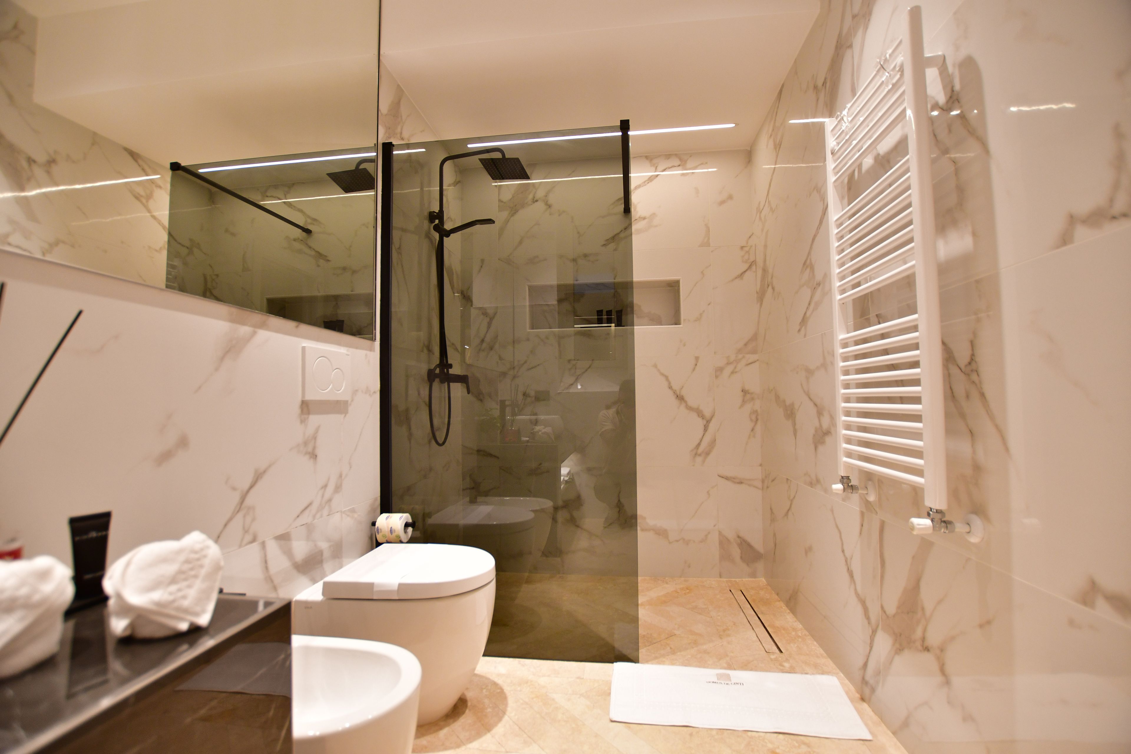 Ein modernes Badezimmer mit einer gläsernen Duschkabine, einer Toilette und einem Waschtisch mit Spiegel.