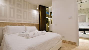 Ein Hotelzimmer mit einem großen Bett, einem Badezimmer mit Spiegel und einer Tür zu einem weiteren Raum.