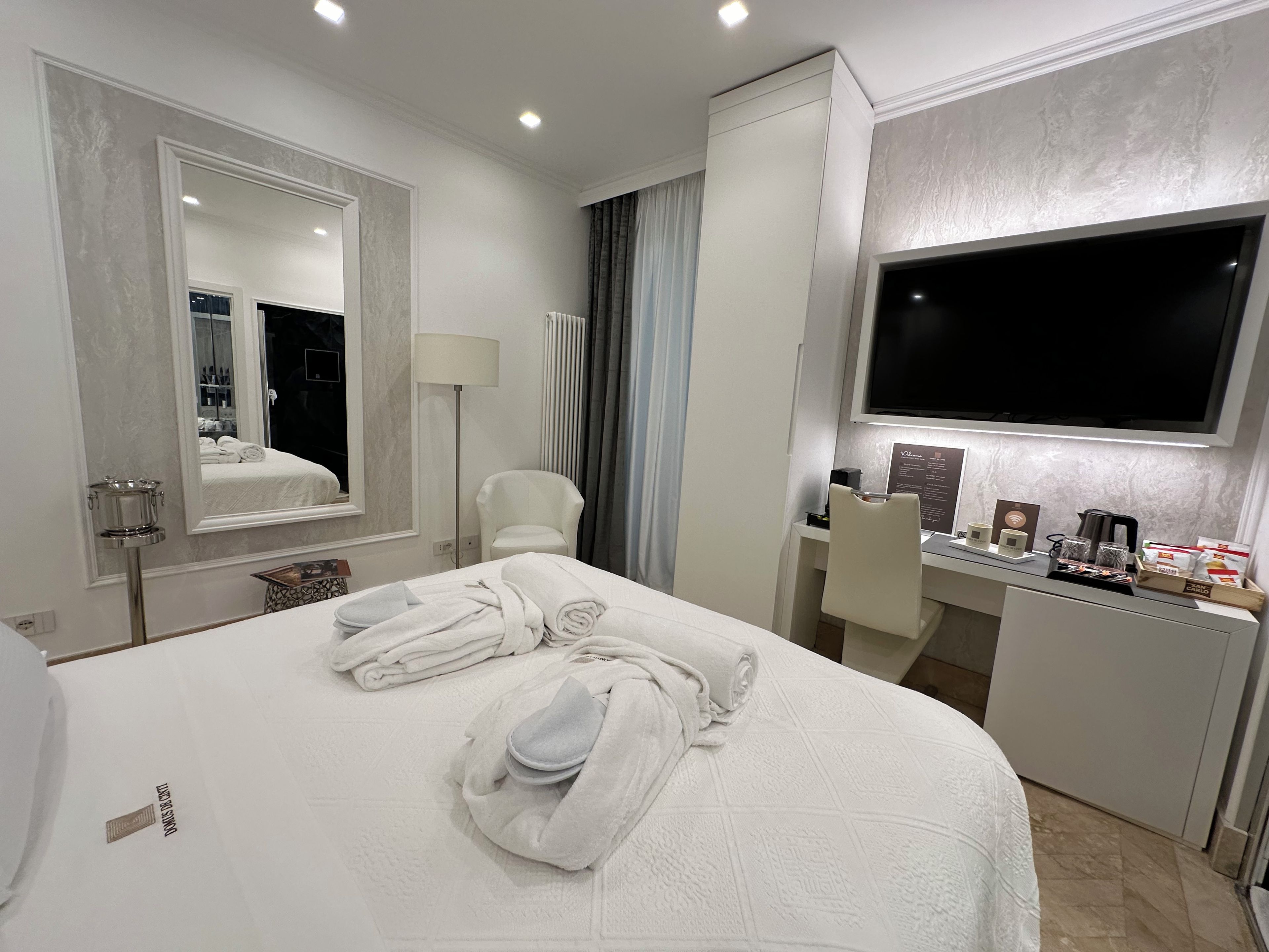 Une chambre d’hôtel avec un grand lit, un bureau doté d’un téléviseur à écran plat, une chaise et un miroir.
