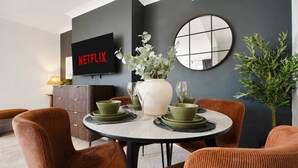 A dining area with a round table, green plates, and a vase of flowers. - Chic 4BR Near Hornsea Museum by Stay With Us (Hornsea)